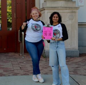Two students holding a clipboard with a voter registration form.