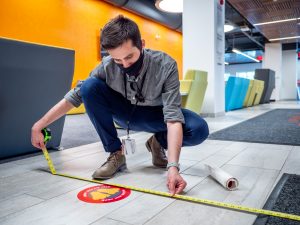 Employee measuring social distance for signage