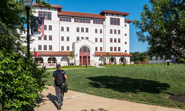 Student walking towards the Feliciano School of Business building.