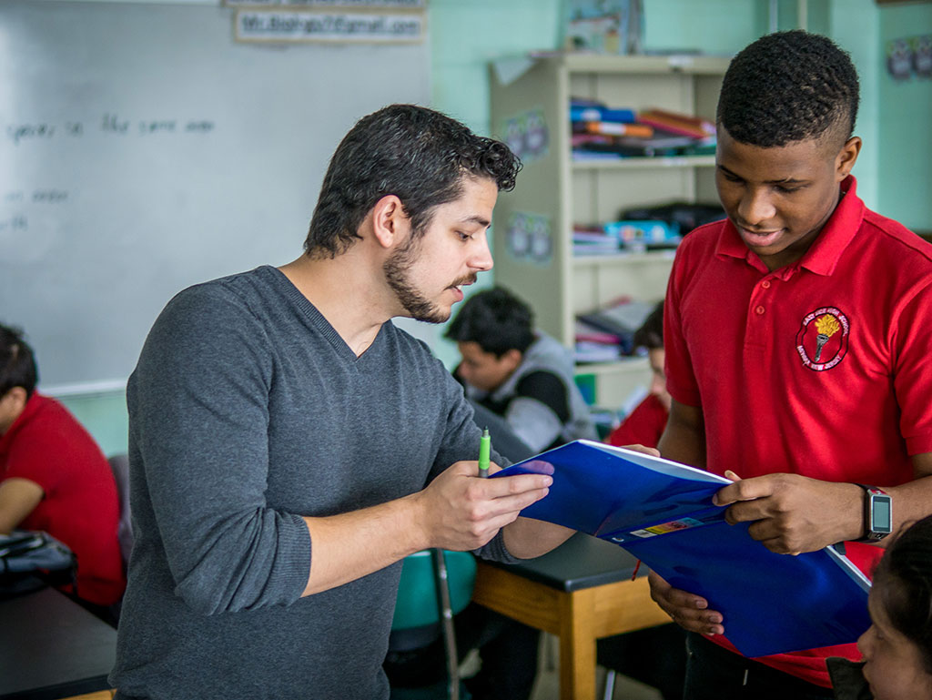 Bilingual biology teacher and residency program graduate Alex Diaz speaking with student.