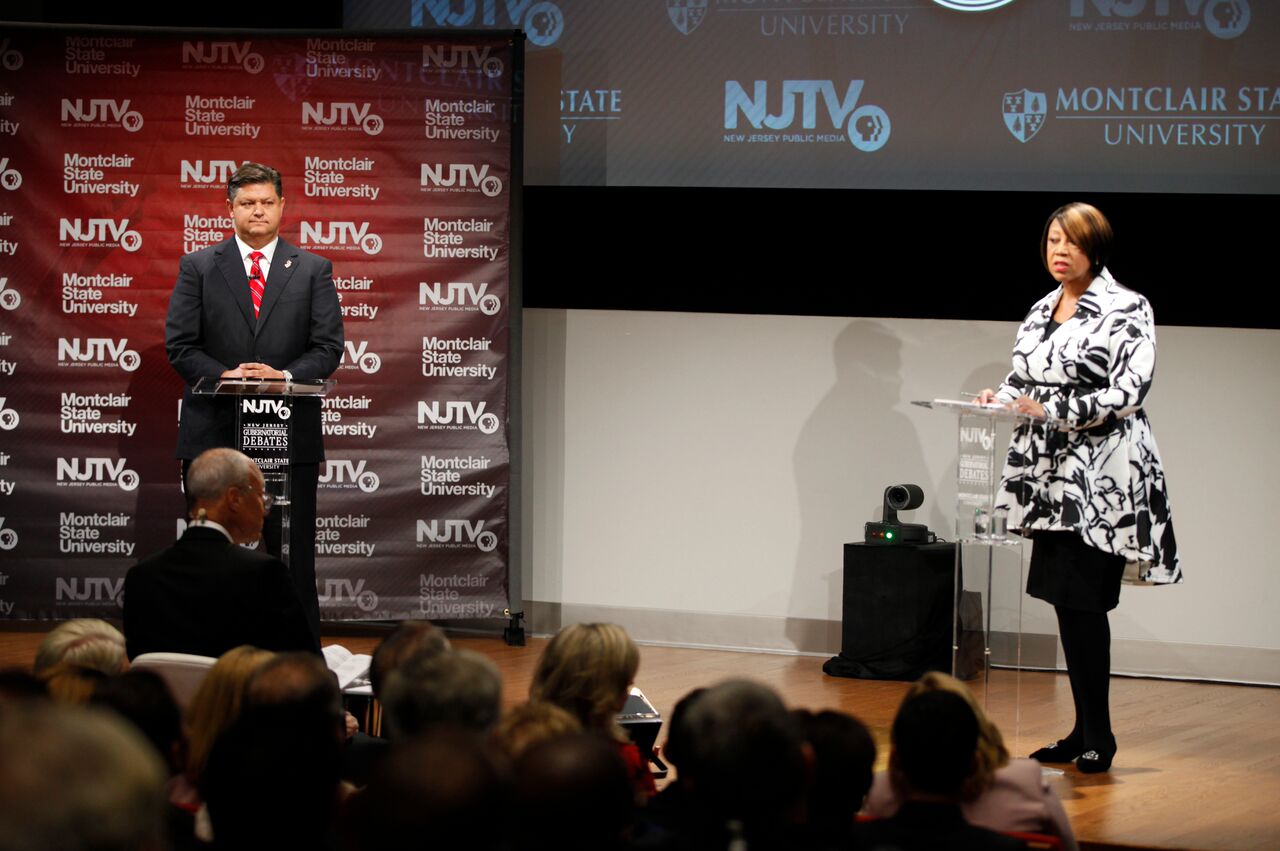 Carlos Rendo and Sheila Oliver debating on stage.