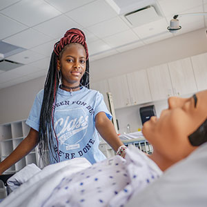 Rokia Fane, freshman in the four-year BSN class, posing with nursing dummy.
