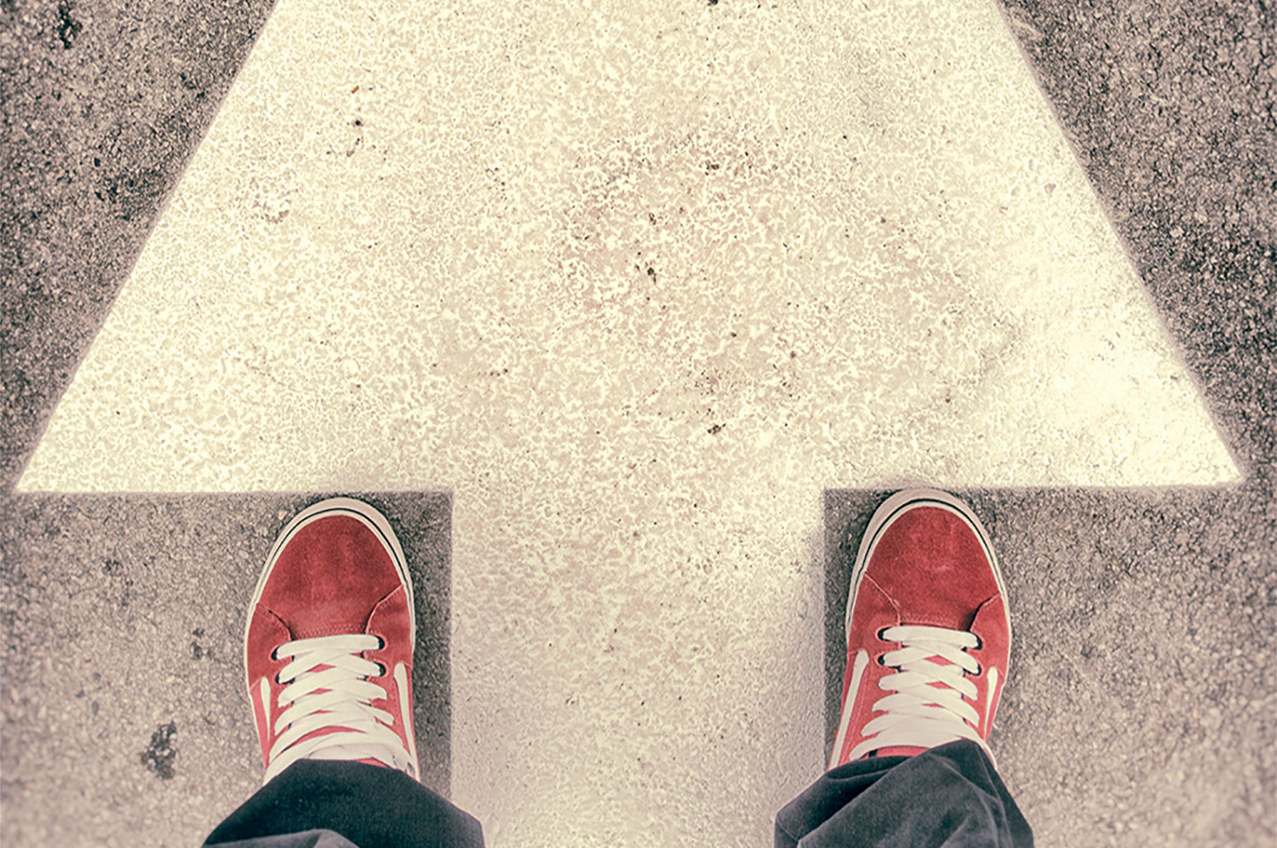 Feet standing on arrow on street