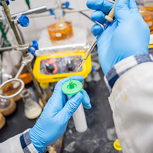 Gloved lab technicians hands injecting something into bottle