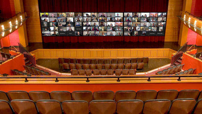 Giant Zoom conference superimposed over stage curtain