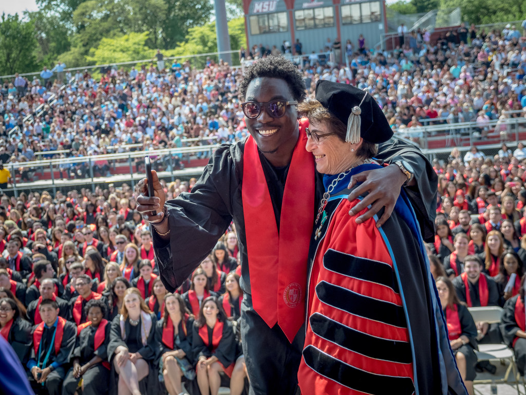 Student with arm around Cole at Commencement