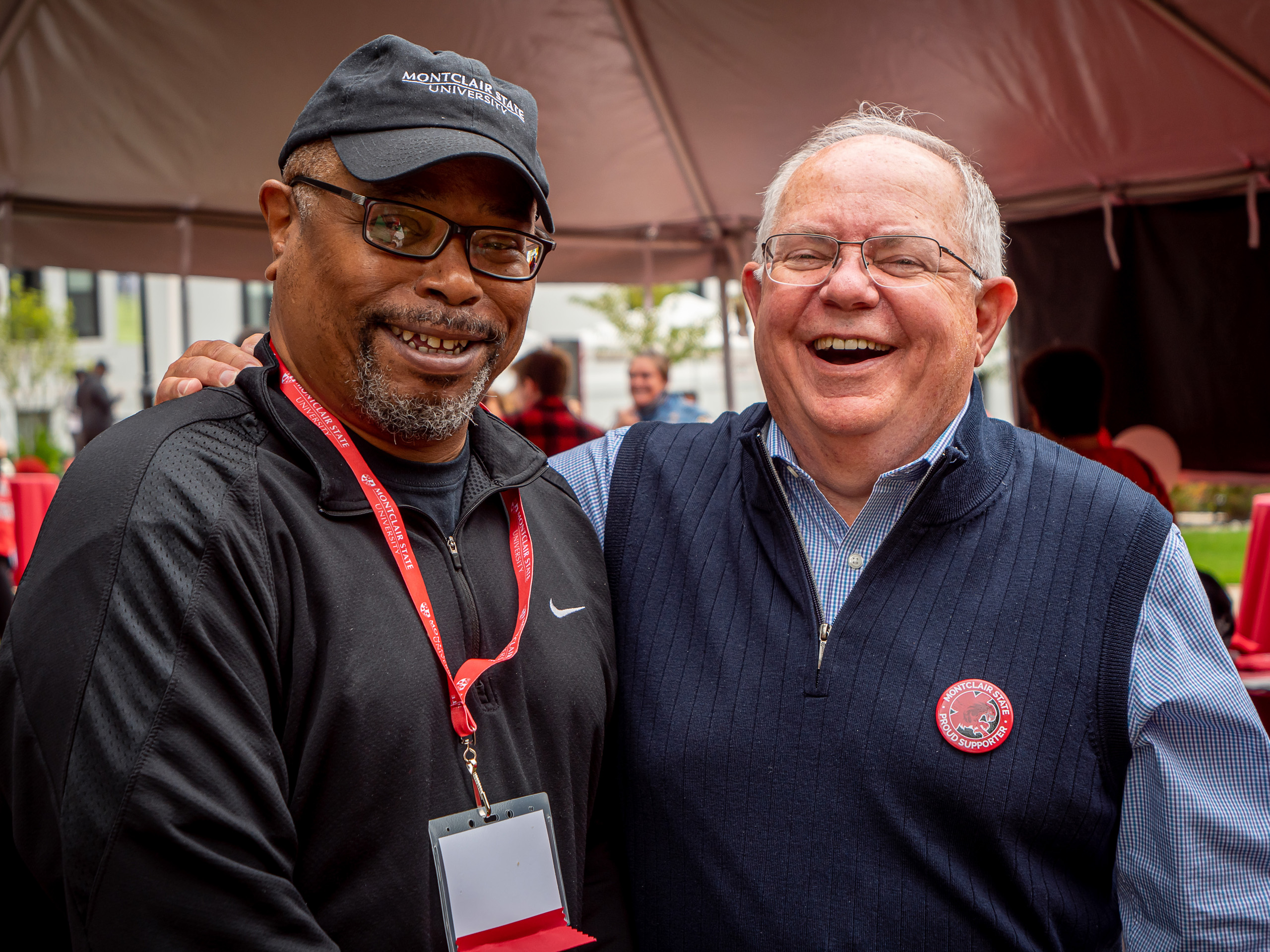 Two alumni hug and smile for the camera