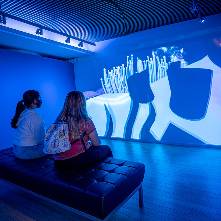 Two students viewing a projection at the Tech/Know/Future exhibit