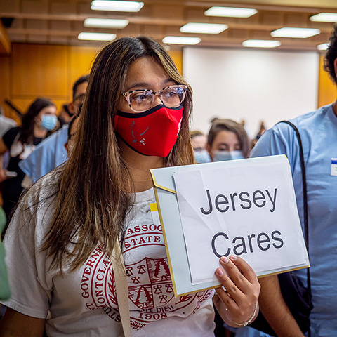 student wearing mask holding "Jersey Cares" sign