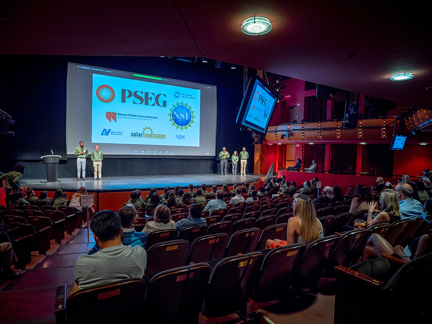 Members of the PSEG Institute on stage in front of a presentation screen