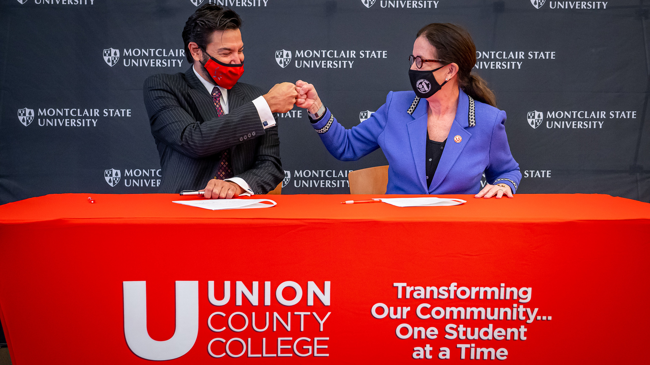 Montclair President Jonathan Koppell and Union President Margaret M. McMenamin do a "fist-bump" at a table after signing an agreement