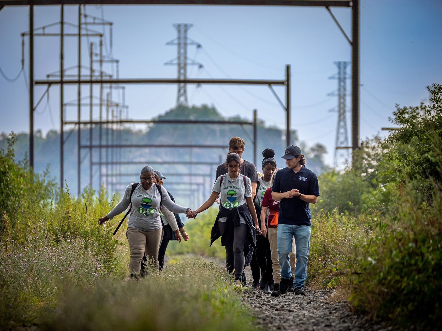 Group of people walking along overgrown railroad tracks