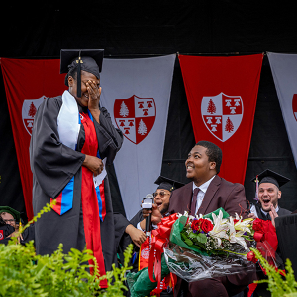 Man proposing to woman in cap and gown on stage