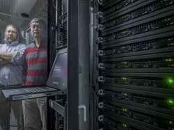 Computer science faculty members posing with rack of servers.