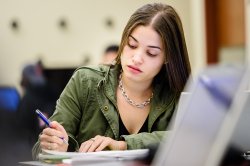 Photo of student taking notes in class