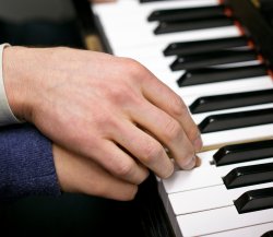 Image of an adult guiding a child's hand on the piano.