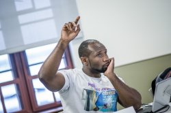 Photo of student raising hand in classroom.
