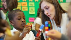 Student teacher works with elementary school student to build a tower