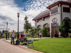 Wide view of student on bench in front of Schmitt Hall