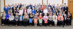 Group picture of the class of 1967 at their 50th reunion. Four members at the bottom row hold up posters that spell out 1967.