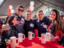 Five alumni posing and smiling at homecoming