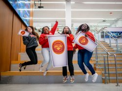 Students jumping and holding cardboard cut outs of coffee cups