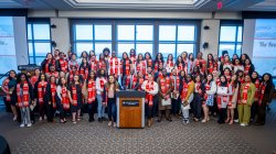 Photo of the graduating class of Montclair State's Educational Opportunity Fund standing in a goup in front of a lectern