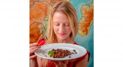 photo of professor Borgerson looking down at a plate of edible bugs with blue and orange world map behind her