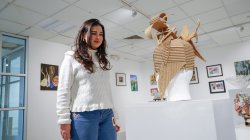 Image of a student standing by artwork in the Finley Gallery