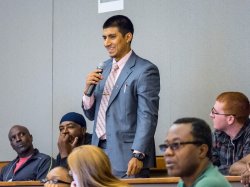 young man in suit holding microphone answering question