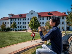 Image of man playing the French Horn outside