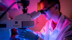 student in water testing lab using microscope
