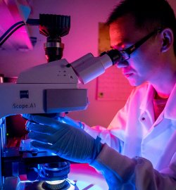 student in water testing lab using microscope