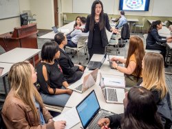 professor speaking to students at group table