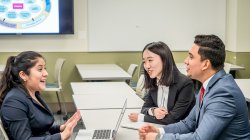 three students speaking at a table