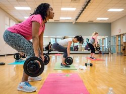 Two people in a group fitness class lifting weights