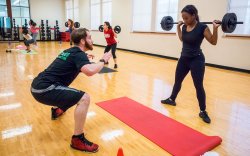 Fitness instructor teaching another how to do squats