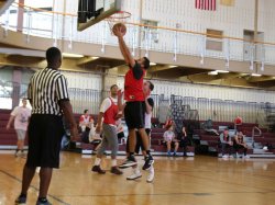 A referee standing on the left and 3 students playing basketball in the rec center gym
