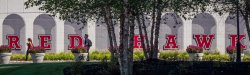 Students walking in front of painted red hawk arches