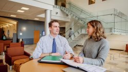 Two students sitting in the CELS building discussing things.