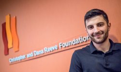 A student standing in front of a sign at his internship.
