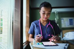 Nurse using digital tablet in hospital room