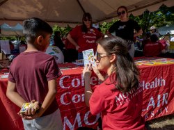 A Dietetics student plays interactive nutrition games with a young festival attendee.