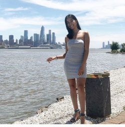 Woman standing on shore with city skyline across the water