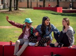 Three students happy, sitting in the quad
