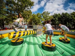 Students on a blow up jumping over a rotating arm.