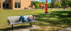 Student in outside of Dickson hall lying on bench