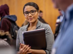 photo of student wearing glasses holding folder at career fair olding fol