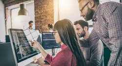 Stock photo of programmers examining code on a large screen
