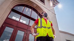 Image of student in yellow vest standing in front of building